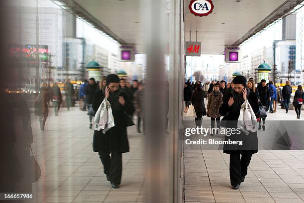 Pedestrian carries shopping bags past the window of a C&A retail store in Warsaw, Poland, on Thursday, April 11, 2013. Poland's central bank kept...