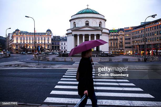 Pedestrian carries an umbrella past a road crossing in central Warsaw, Poland, on Thursday, April 11, 2013. Poland's central bank kept interest rates...