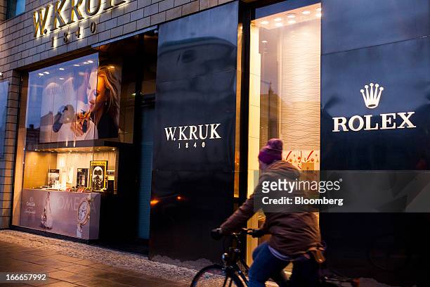 Cyclist passes the window displays of a W. Kruk jewelry store advertising Rolex watches in Warsaw, Poland, on Thursday, April 11, 2013. Poland's...