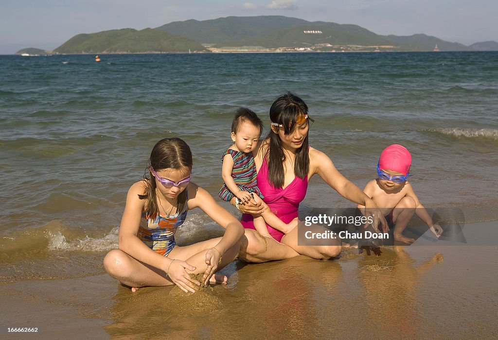 A Vietnamese woman plays with her kids on Nha Trang beach,...