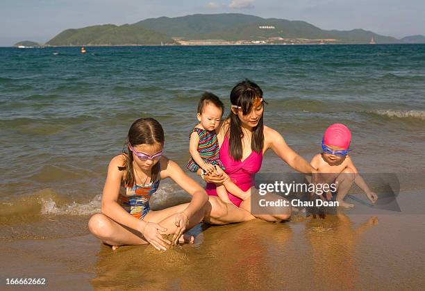 Vietnamese woman plays with her kids on Nha Trang beach, one of the best beaches in Vietnam. Vietnamese tourism has been one of the fastest growing...