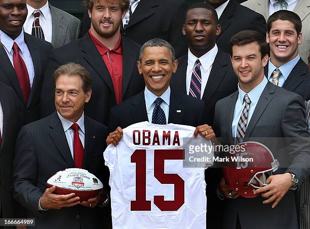 President Barack Obama , holds a jersey presented to him by coach Nick Saban and Quaterback A.J. McCarron , while honoring the BCS National Champion...