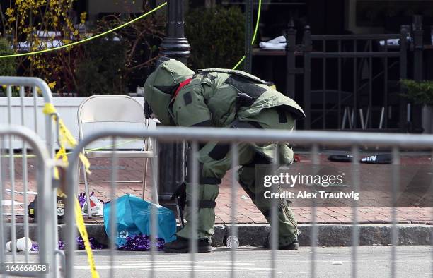 Member of the bomb squad investigates a suspicious item on the road near Kenmore Square after two bombs exploded during the 117th Boston Marathon on...