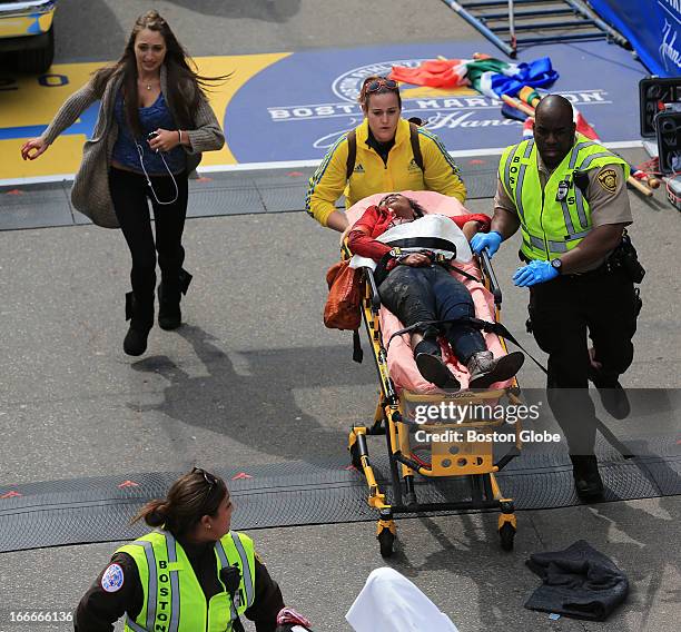 Person who was injured in an explosion near the finish line of the 117th Boston Marathon is taken away from the scene on a stretcher.