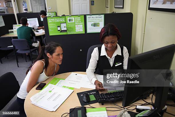 Jackie Duong sits with Sandra Johnson Darby, tax associate, as she does her taxes at the H&R Block office on April 15, 2013 in Miami Beach, Florida....