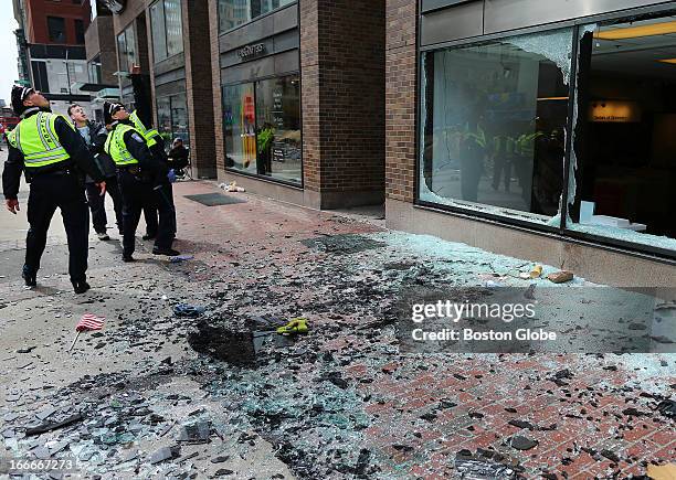 Boston Police look at blown out windows at the scene of the first explosion on Boylston Street near the finish line of the Boston Marathon.