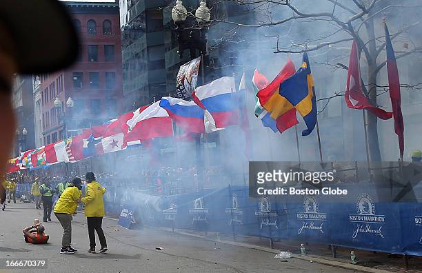 Officials react as the first explosion goes off on Boylston Street near the finish line of the 117th Boston Marathon on April 15, 2013.