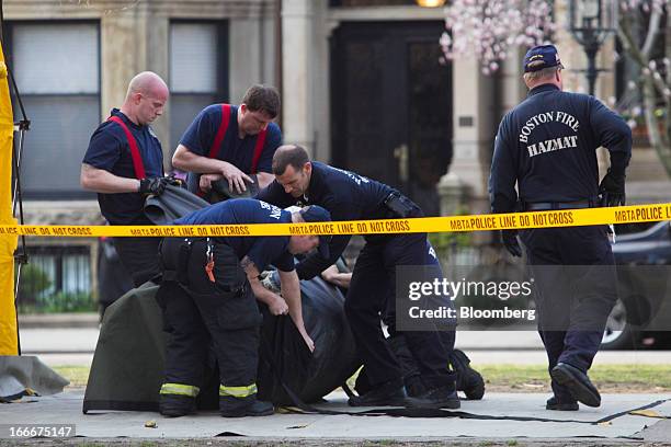 Officials with the Boston Fire Department Hazardous Materials Unit wrap up a garbage can along Commonwealth Avenue after two explosions occurred...