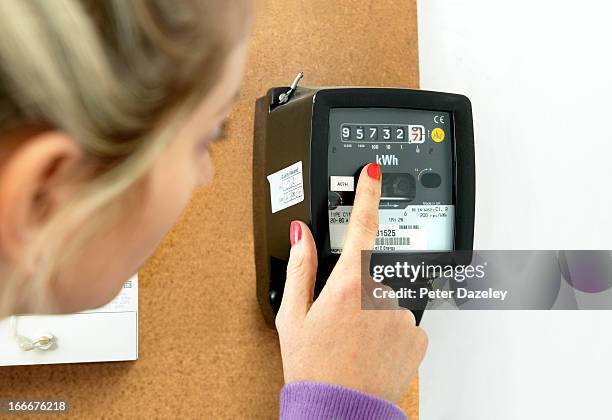 woman reading electric meter - elektriciteitsmeter stockfoto's en -beelden