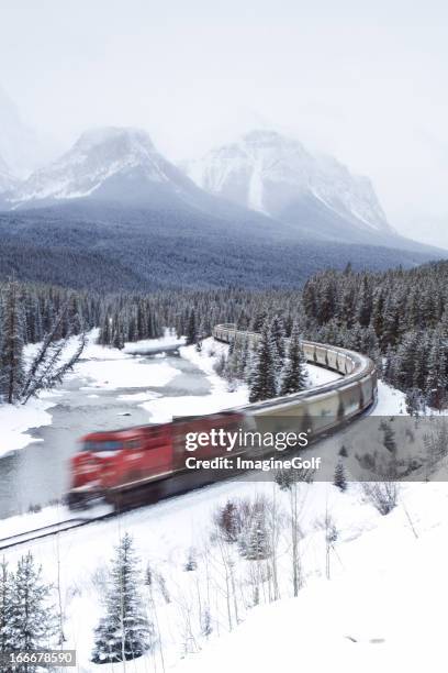 red train speeding through rocky mountains - banff snow stock pictures, royalty-free photos & images