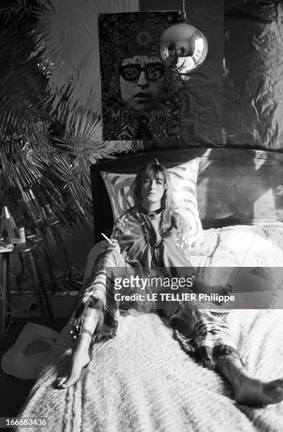 Jane Birkin And John Crittle In London. Angleterre, Londres, 28 septembre 1967, un mannequin habillé à la mode hippie pose sur son lit, une cigarette...