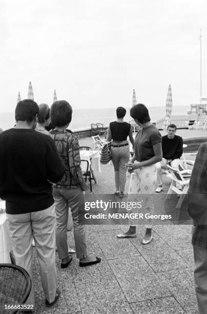 Biarritz. Biarritz- 23 Août 1961- Loisirs: sur une terrasse, jeunes gens se retournant sur une jeune femme en pantalon et maillot court montrant sa...