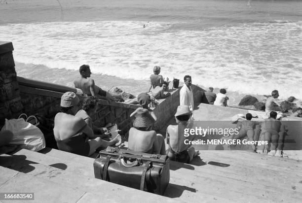 Biarritz. Biarritz- 23 Août 1961- Loisirs: plan plongeant sur un escalier donnant sur la plage, l'écume en arrière-plan, un sac de voyage fermé posé...