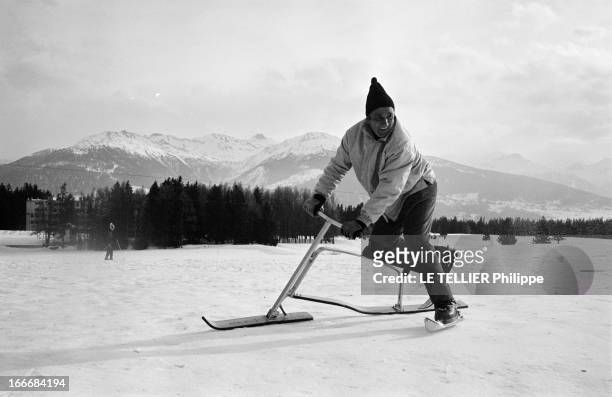 The Snow Bicycle. En Suisse, à Crans-Montana, 17 février 1967, sur une piste de ski, l'acteur Lino VENTURA riant sur un ski-bob, un genou posé sur un...