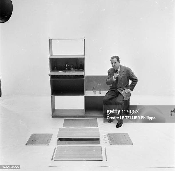 Ancient And Modern Furniture In The Fifties. En 1955, en studio sur fond neutre, un homme avec un fume cigarette présente une pièce de mobilier pour...