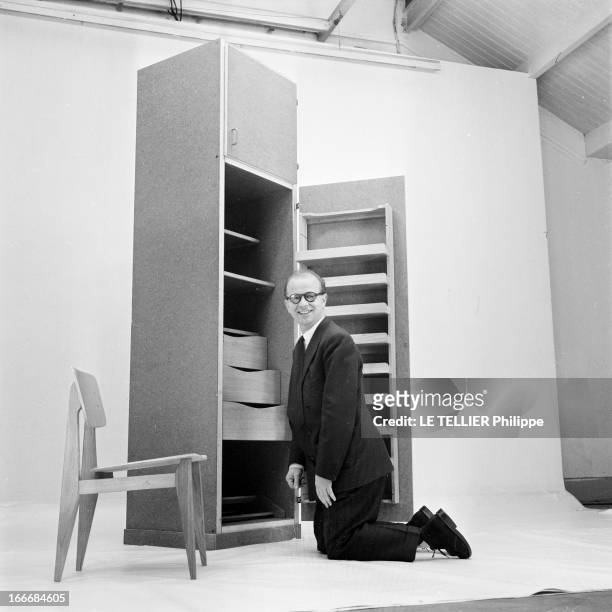 Ancient And Modern Furniture In The Fifties. En 1955, en studio sur fond neutre, un homme à genoux présente un élément de mobilier pour la maison aux...