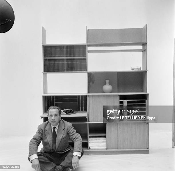 Ancient And Modern Furniture In The Fifties. En 1955, en studio sur fond neutre, un homme assis par terre présente un ensemble de mobilier pour la...