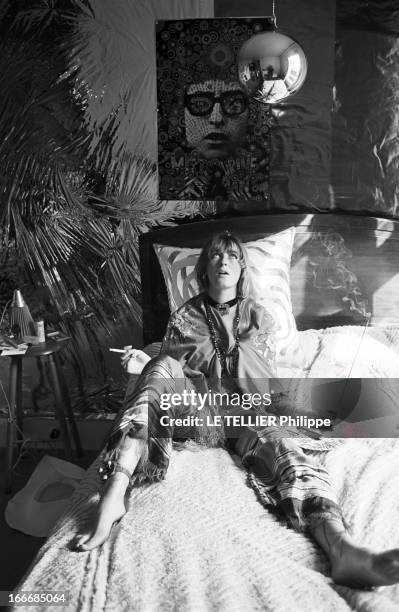 Jane Birkin And John Crittle In London. Angleterre, Londres, 28 septembre 1967, un mannequin habillé à la mode hippie pose sur son lit, une cigarette...