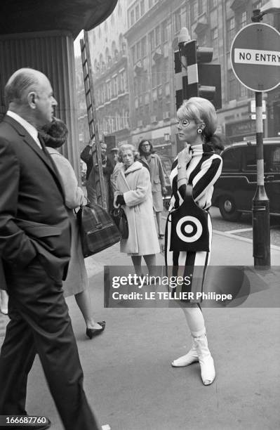 Op Art Make-Up In London. A Londres, dans la rue, le modèle Eve, les yeux entourés d'un maquillage 'Op Art', portant une robe, des collants et un sac...