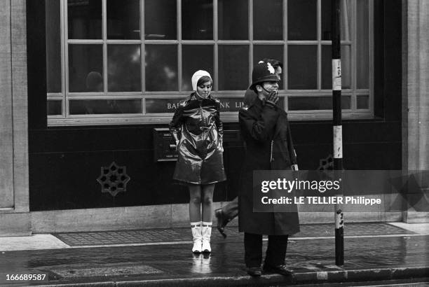 Op Art Make-Up In London. A Londres, dans la rue, le modèle Kari-Ann, les yeux entourés d'un maquillage 'Op Art' portant un imperméable ciré sur une...