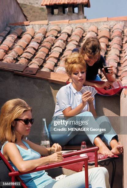 Vips On Holiday In Saint-Tropez. Saint-Tropez - juillet 1963 - Sur une terrasse, l'actrice Annette STROYBERG jouant aux cartes, assise sur un banc en...