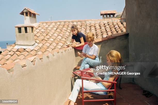 Vips On Holiday In Saint-Tropez. Saint-Tropez - juillet 1963 - Sur une terrasse, l'actrice Annette STROYBERG jouant aux cartes, assise sur un banc en...