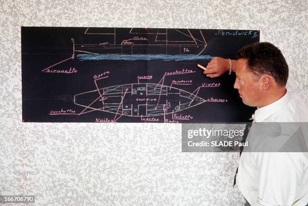 Eric Tabarly Wins The Transatlantic Solo Race Plymouth Newport 1964. Un homme non-identifié, de profil, en chemise cravate, tenant une craie, debout...
