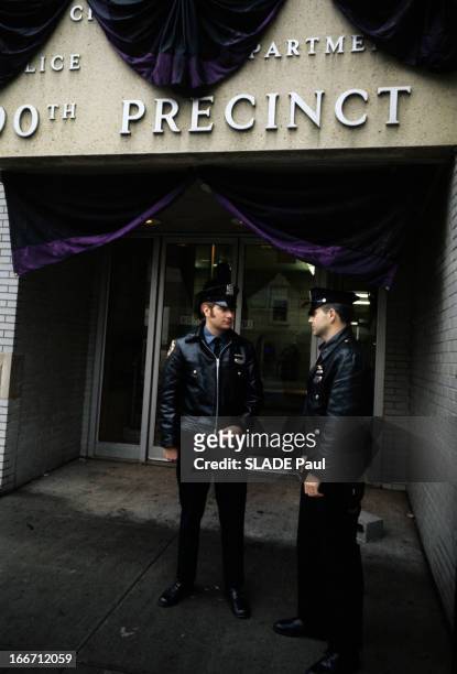 New York, World Capital Of Violence. A New-York, deux policiers, en blouson de cuir et casquette,debout devant l'entrée d'un commissariat de police,...