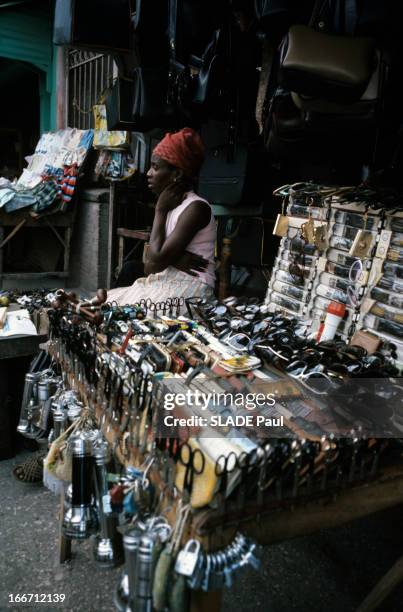 Haiti. A Haiti, en janvier 1973, lors d'un reportage dans le pays, sur un marché une femme portant un foulard, vendant des lunettes de soleil, des...