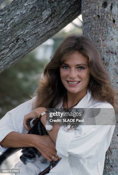 Rendezvous With Jacqueline Bisset. Portrait en extérieur de Jacqueline BISSET, en chemisier, adossée à un arbre, tenant un chaton dans ses bras.