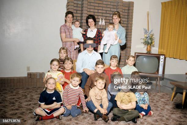 Salt Lake City Mormons, Utah. Dans l'Utah, dans une pièce avec une télévision, une famille polygame mormone, le père, portant un masque, assis parmi...