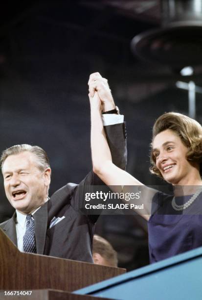 Nelson Rockefeller And His Wife. Aux Etats-Unis, Nelson ROCKFELLER, en costume cravate, debout derrière un pupitre, levant le bras en tenant la main...