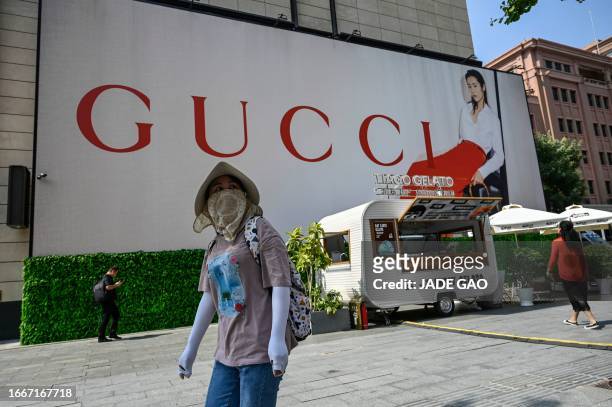 Woman walks past a billboard for Italian luxury fashion brand Gucci at a shopping mall in Beijing on September 15, 2023.