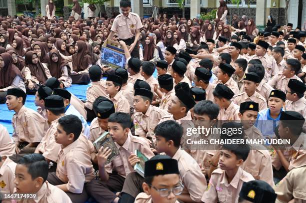 Islamic junior high school students donate after taking part in a Quran recitation and making special prayers for the victims of the earthquake in...