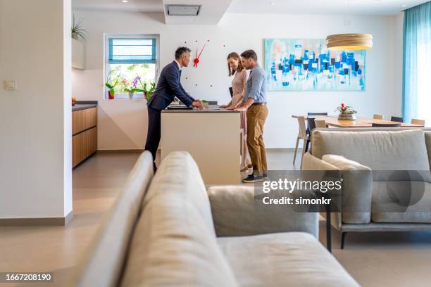 male real estate agent showing brochure to couple - luxury home dining table people lifestyle photography people stock pictures, royalty-free photos & images