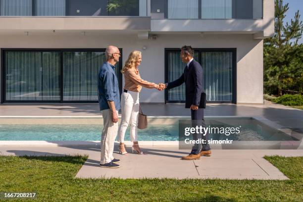 male real estate agent shaking hand with couple - corretor de imoveis imagens e fotografias de stock