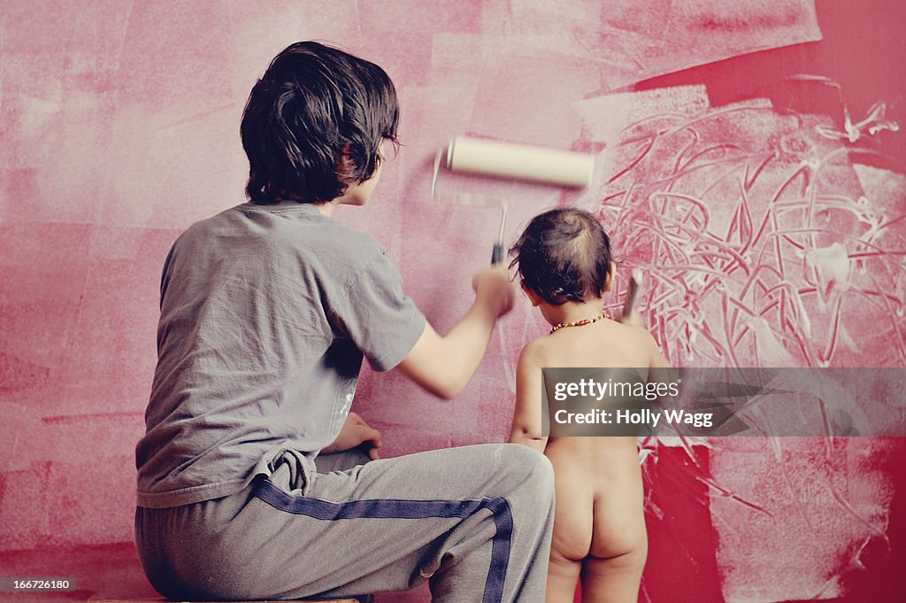 Teenager and toddler child paint wall