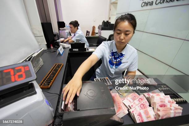 Staff member counts Chinese Yuan at a bank's personal finance business service area in Haian, East China's Jiangsu province, Sept 15, 2023. The...