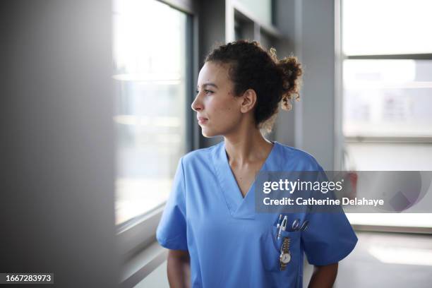a nurse posing in a hospital corridor - female nurse stock pictures, royalty-free photos & images