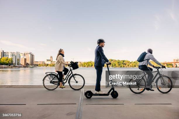male and business people commuting through cycles and electric push scooter on promenade - scooter city fotografías e imágenes de stock