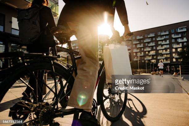 midsection of non-binary person riding bicycle on footpath at sunset - non motorised vehicle stock pictures, royalty-free photos & images