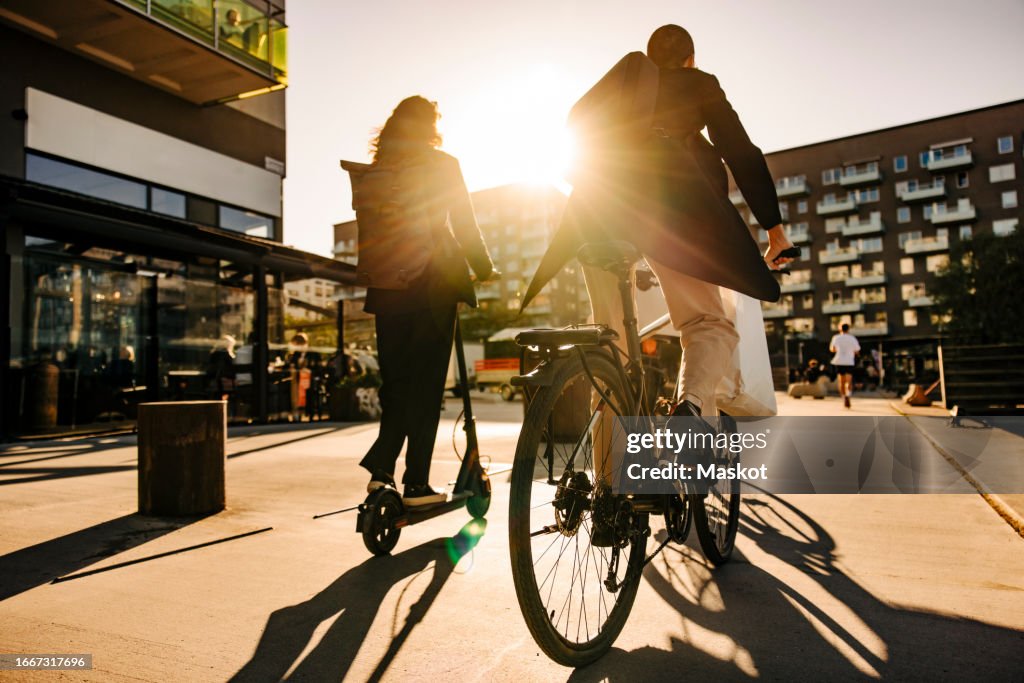Business people commuting sustainably on promenade at sunset