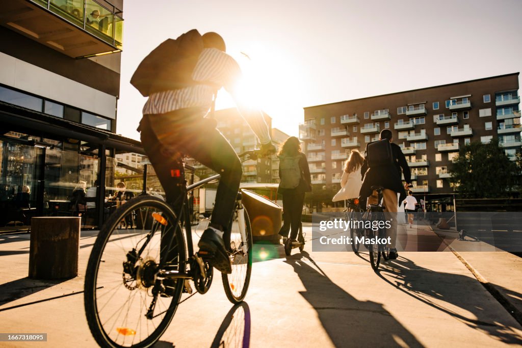 Business people commuting through bicycles on promenade at sunset