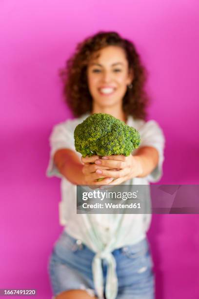 happy woman holding broccoli and standing against magenta background - broccoli white background stock pictures, royalty-free photos & images