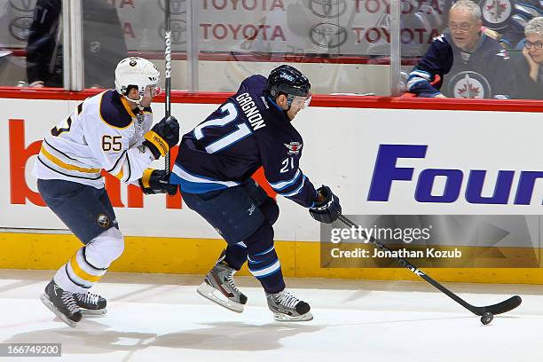 Aaron Gagnon of the Winnipeg Jets plays the puck along the boards as Brian Flynn of the Buffalo Sabres gives chase during first period action at the...