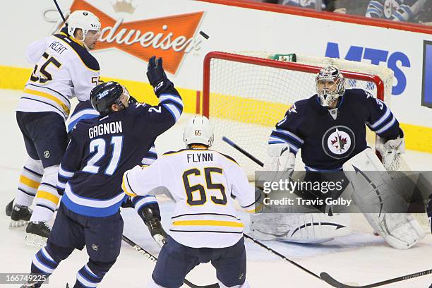 Goaltender Ondrej Pavelec of the Winnipeg Jets watches as teammate Aaron Gagnon tries to bat the puck away from Brian Flynn of the Buffalo Sabres at...