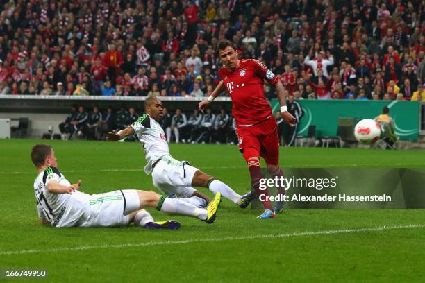 Mario Mandzukic of Muenchen scores the opening goal against Alexander Madlung of Wolfsburg and his team mate Naldo during the DFB Cup Semi Final...