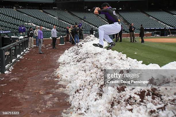 Pitcher Rex Brothers of the Colorado Rockies jumps over a snow bank to get to the dugout as workers remove snow from the field as the New York Mets...