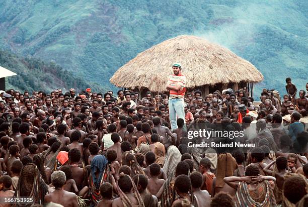 Missionary speaks in a local language to a group in a mountain tribe settlement of Dani people..