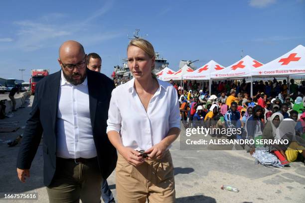 French far right party Reconquete leaders Marion Marechal and Philippe Vardon walk by migrants waiting on a dock as they visit the Lampedusa port...